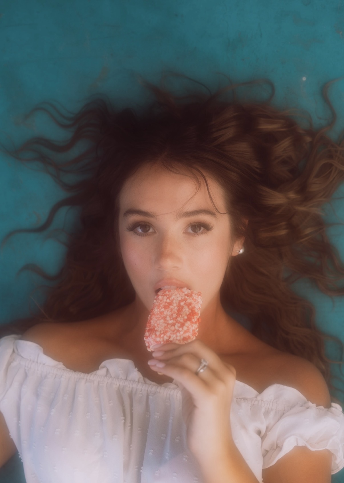 MACY. lying on a teal background, holding an ice cream bar.