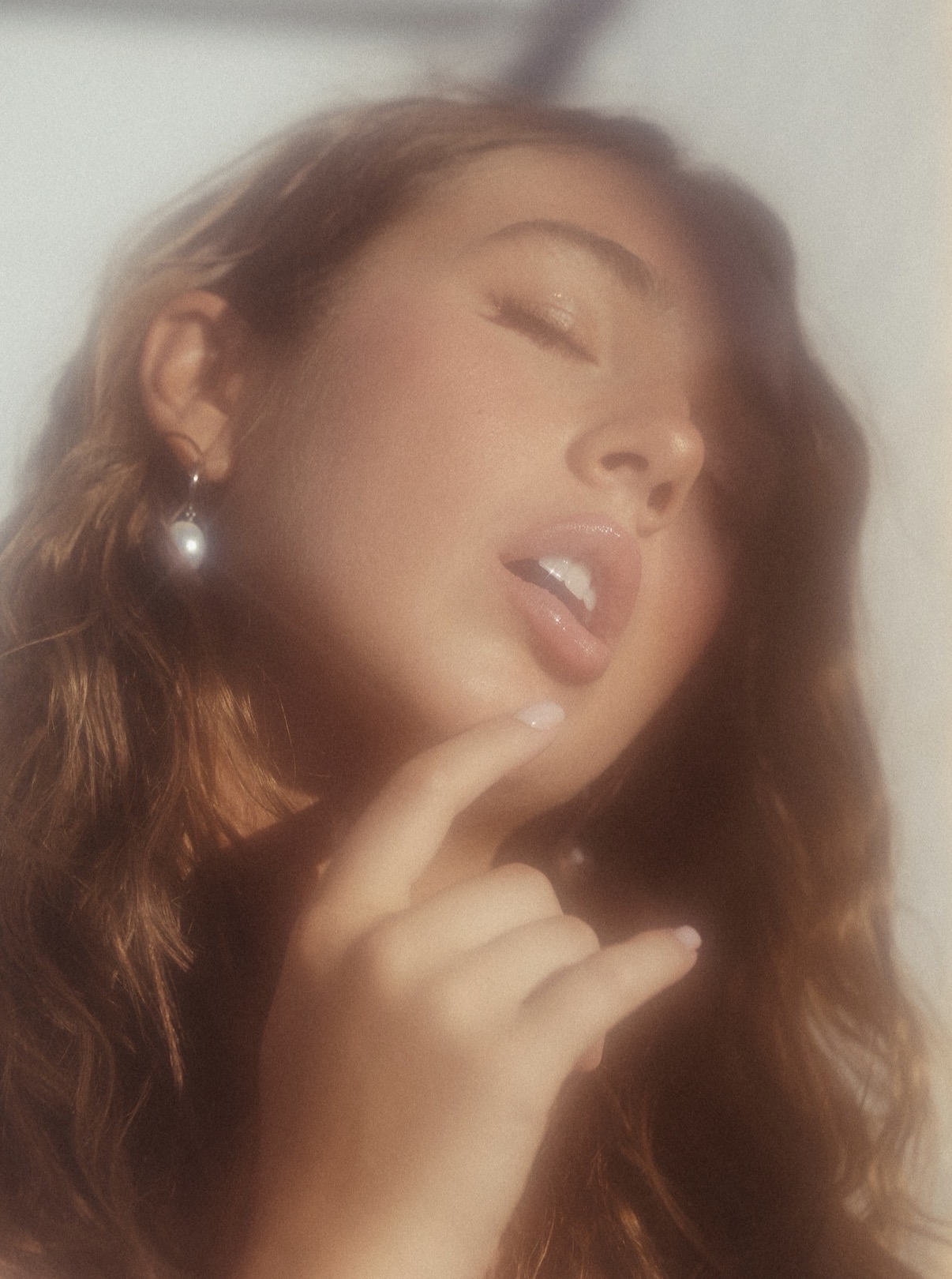 A soft, reflective portrait of MACY. with her finger near her chin.